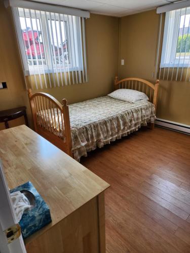 a small bedroom with a bed and two windows at Appartement de la rive 2 in Shippagan