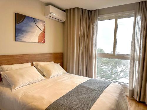 een slaapkamer met een bed en een groot raam bij Luxuoso Studio no Serra Class (307) in Canela