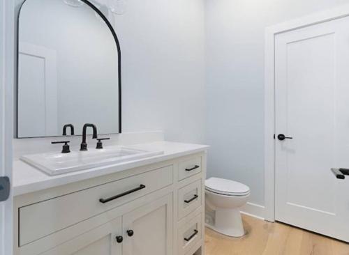 a white bathroom with a sink and a toilet at Luxury Home 4B, 3B Sleeps 18 25min to Nashville in Greenlawn