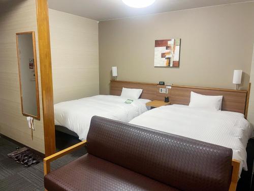 a hotel room with two beds and a couch at Hotel Route-Inn Nagaizumi Numazu Inter 2 in Nagaizumi