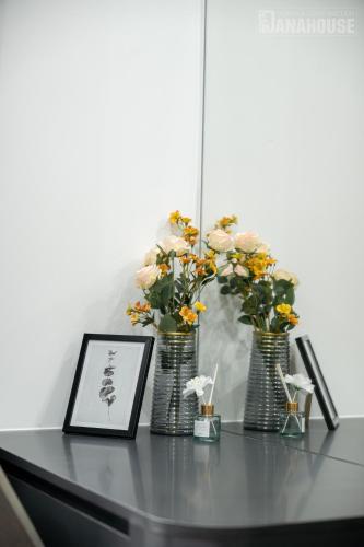 two vases with flowers and a picture on a table at Khách sạn Trung Trầm in Dong Hoi