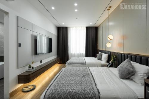 a hotel room with two beds and a television at Khách sạn Trung Trầm in Dong Hoi