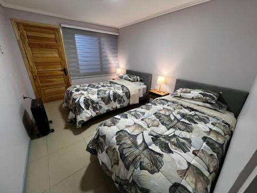 a bedroom with two beds and a window at Pewma House, by Pewma Apart Hotel in Chillán