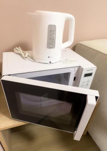 a microwave with a coffee pot on top of it at Rakuyado Shinimamiya in Osaka