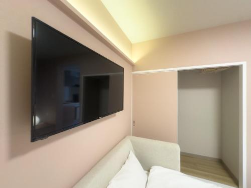 a living room with a large flat screen tv on the wall at Rakuyado Shinimamiya in Osaka
