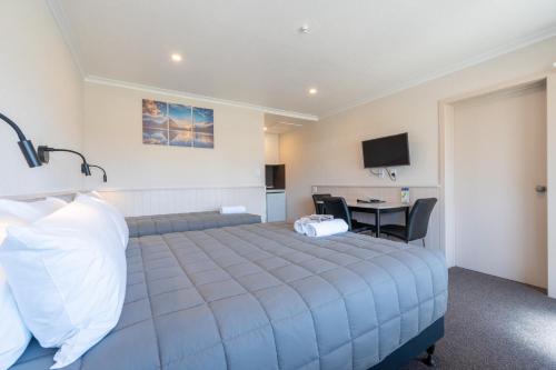 a bedroom with a bed and a desk and a television at Te Anau Top 10 Holiday Park and Motels in Te Anau