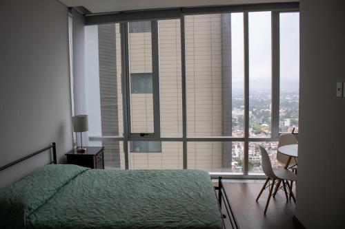 a bedroom with a green bed and a large window at Condo con Alberca a un Paso del Estadio Azteca in Díaz