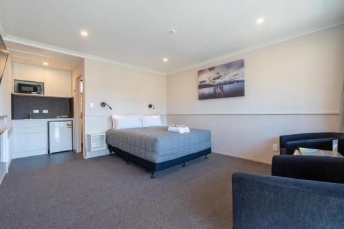 a bedroom with a bed and a living room at Te Anau Top 10 Holiday Park and Motels in Te Anau