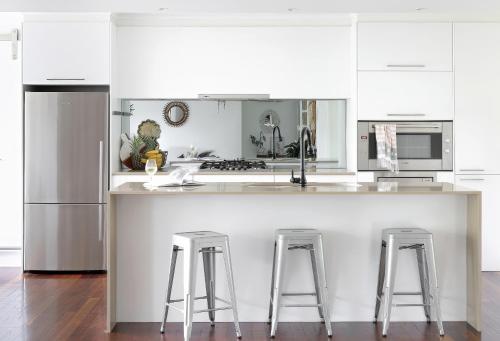 a kitchen with white cabinets and a counter with stools at Buderim Rainforest Retreat - 10 mins to Mooloolaba in Buderim