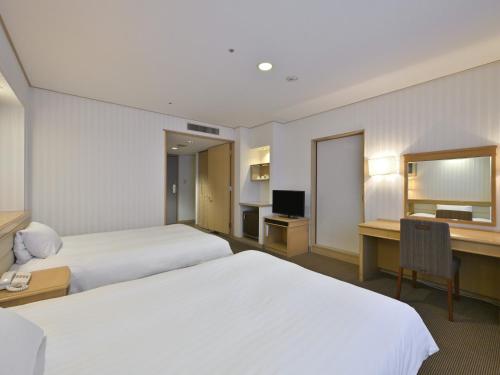 a hotel room with two beds and a desk at Rihga Hotel Zest Takamatsu in Takamatsu