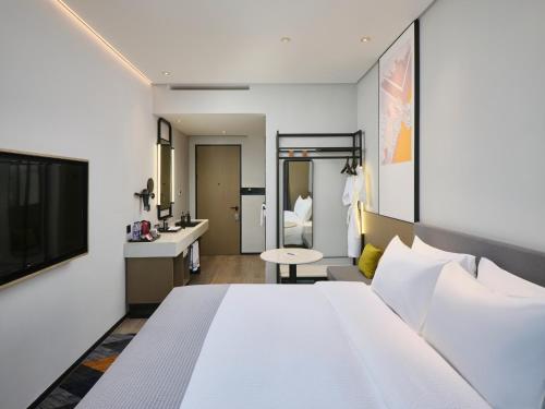 a hotel room with a bed and a bathroom at Wanda Moments Nanchang in Xinjian