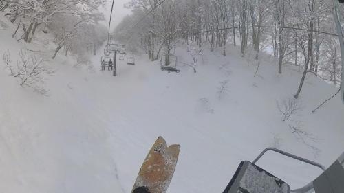 a person riding a ski lift in the snow at Juniya Myoko in Myoko