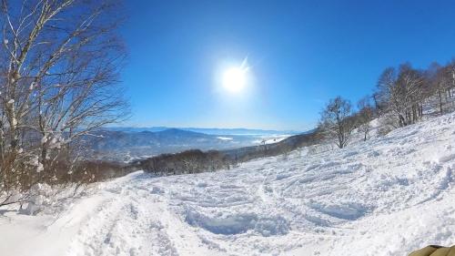 a snow covered hill with the sun in the sky at Juniya Myoko in Myoko