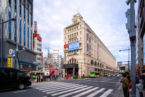 a busy city street with a tall building with a tower at Yahiro 4-chome House 2F,3F in Tokyo