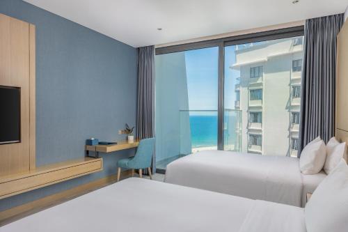 a hotel room with two beds and a view of the ocean at Awaken Da Nang Hotel in Da Nang