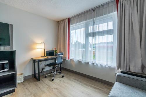 a room with a desk with a computer and a window at Ramada by Wyndham Kingston in Kingston