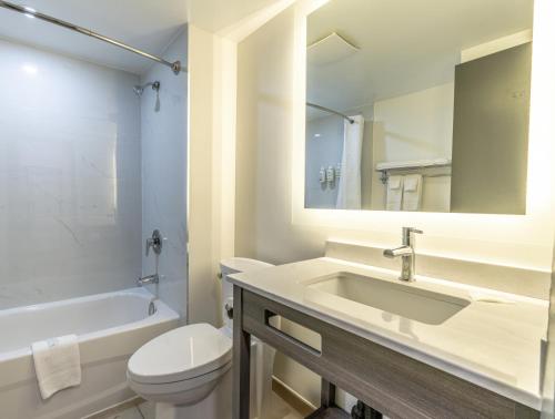 a white bathroom with a sink and a toilet at Ramada by Wyndham Kingston in Kingston