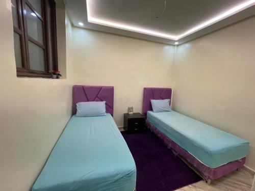 two beds in a room with purple and green at Appartement agadir in Agadir