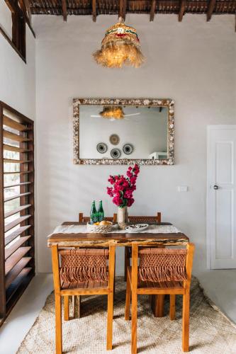a dining room table with a vase of flowers on it at Aore Paradise - Near Santo, Vanuatu in Aore Island