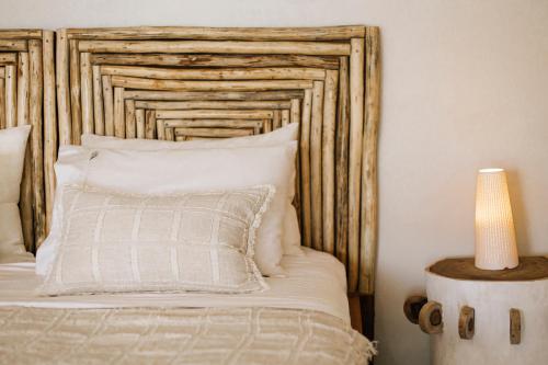 a bed with a wooden headboard with a pillow and a lamp at Aore Paradise - Near Santo, Vanuatu in Aore Island