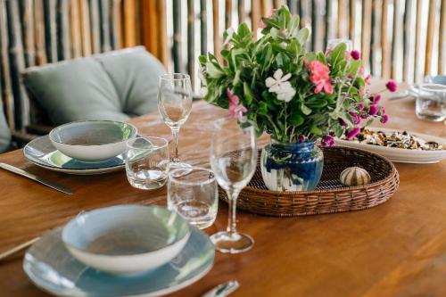 a table with a vase of flowers and wine glasses at Aore Paradise - Near Santo, Vanuatu in Aore Island