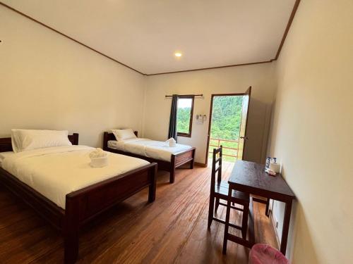 a hotel room with two beds and a table and a table sidx sidx at Konglor Cave Resort-Riverside Restaurant in Ban O