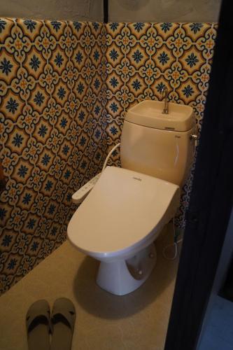 a bathroom with a toilet and a pair of shoes at 錦町の宿路地屋 in Takamatsu