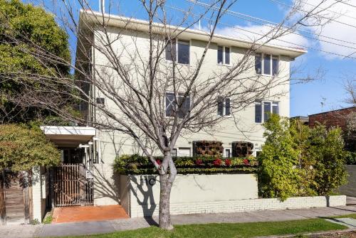 a white house with a tree in front of it at Windsor Apartments by Urban Rest in Melbourne