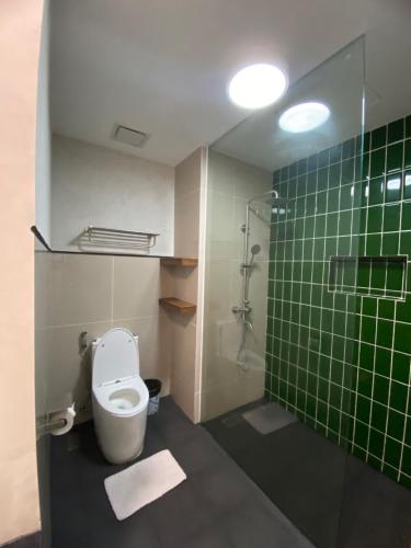 a bathroom with a toilet and a green tiled wall at Buena Casa Hotel in Olongapo