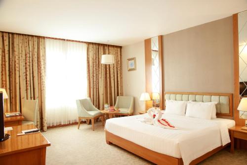 a hotel room with a bed and a table and chairs at Sai Gon Dong Ha Hotel - a member of Saigontourist Group in Quảng Trị