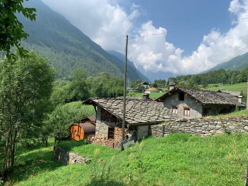 an old stone house in a field with mountains in the background at Lu Biulè di Pau in Groscavallo