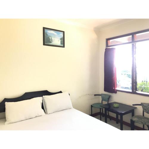 a bedroom with a large bed and a window at Hotel Lie Mas Prigen Pasuruan Mitra RedDoorz in Pasuruan