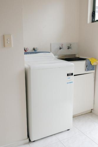 a kitchen with a white refrigerator in a room at Prime location at Mt Eden- Cozy Vibe 3BR Home in Auckland