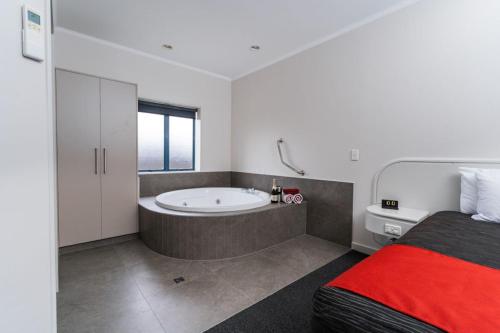 a bedroom with a bed and a tub in a bathroom at Aubyn Court Spa Motel in Palmerston North