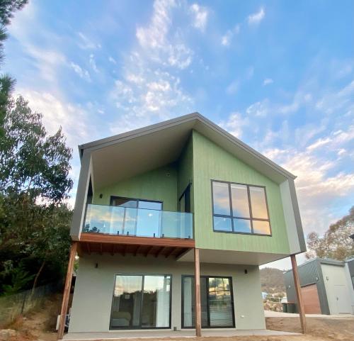 ジンダバインにあるJindabyne House 2, Modern 3 bedroom home, lake & mountain views with fireplaceのバルコニー付きのグリーンハウスです。