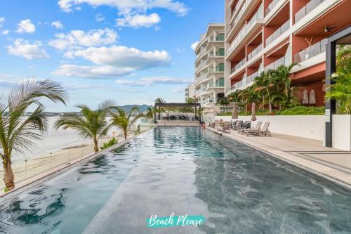 a swimming pool at a resort with a view of the ocean at Casa del Mar Bucerias - Beachfront Condos in Bucerías