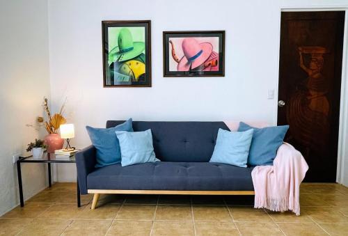a blue couch in a living room with paintings on the wall at New modern & Cozy Private Space! A/C in General Viejo