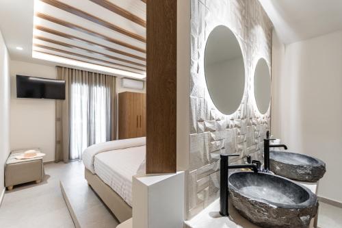 a bedroom with a tub and a bed with a mirror at Perla Hotel in Agios Prokopios
