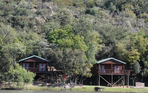 two wooden cabanas on the shore of a body of water at ATKV Klein-Kariba in Bela-Bela