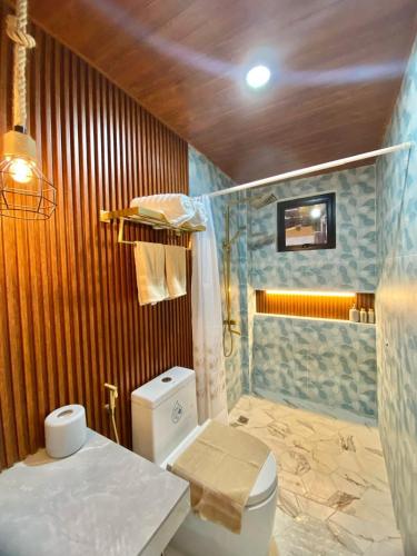 a bathroom with a white toilet and a shower at Villa Yumi in Lucena