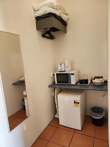 a small kitchen with a microwave and a refrigerator at Inverell Motel in Inverell