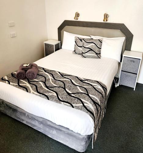 a bed with a black and white blanket and pillows at Inverell Motel in Inverell