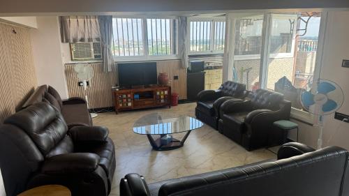 a living room with leather couches and a tv at Riverfront Penthouse Studio with Spacious Terrace in Lucknow