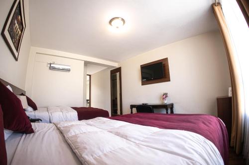 a hotel room with two beds and a tv at Bella AQP in Arequipa