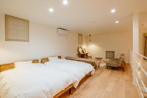 a bedroom with a large white bed and a chair at NAGAHAMA lifestyle glamping hotel in Nagahama