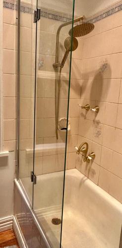 a shower with a glass door next to a tub at The Sister Cottage in Kalorama