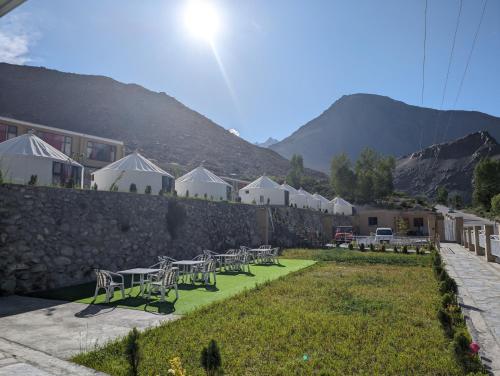 a row of tables and chairs in a yard with mountains at Apex Hotels and Resorts Hussaini in Hunza