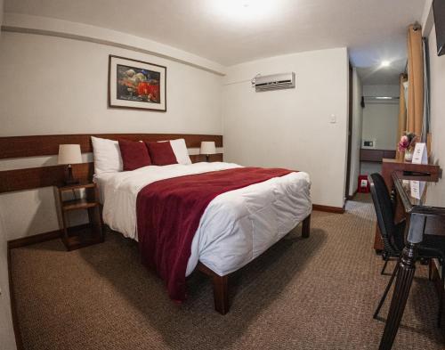 a bedroom with a large bed with a red blanket at Bella AQP in Arequipa