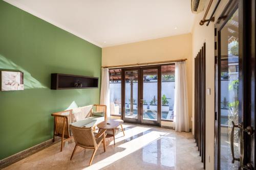 a dining room with green walls and a table and chairs at The Club Villas Seminyak in Seminyak