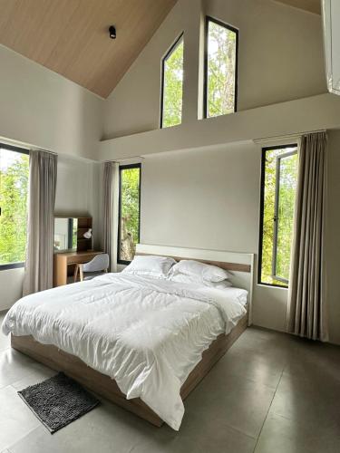 a bedroom with a large white bed with windows at Sokview Residence in Luang Prabang